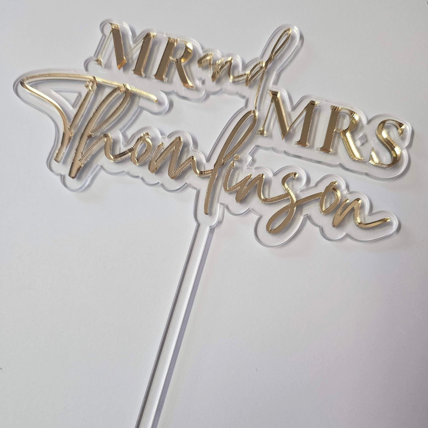 Elegant gold mirror acrylic Mr. & Mrs. wedding cake topper with custom last name, designed for a stylish and personalized touch on any wedding cake.