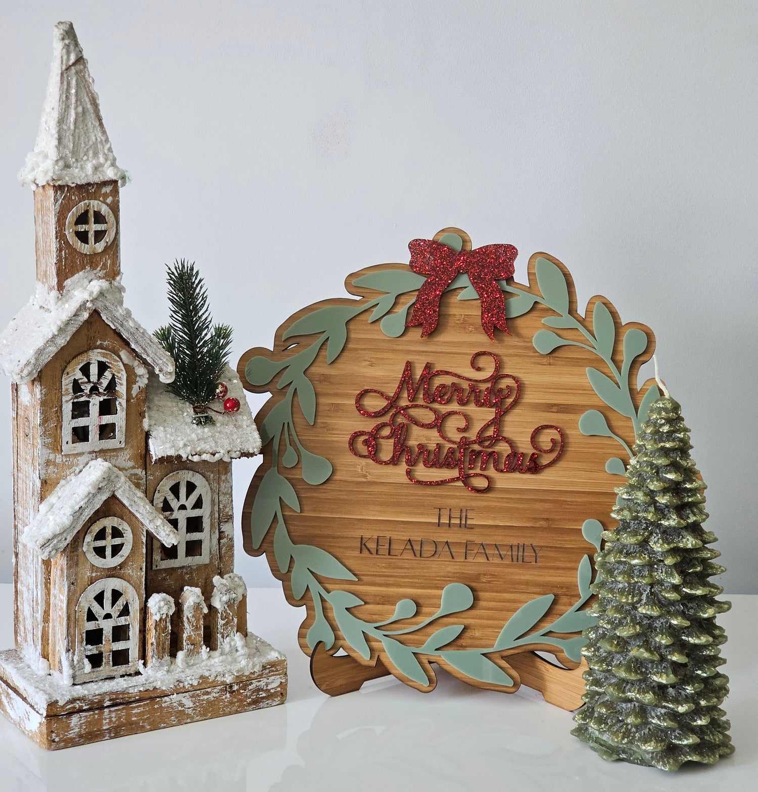 Personalised timber Christmas plaque featuring red glitter “Merry Christmas” text, custom family name, and festive wreath design—ideal for holiday home décor or gifting.