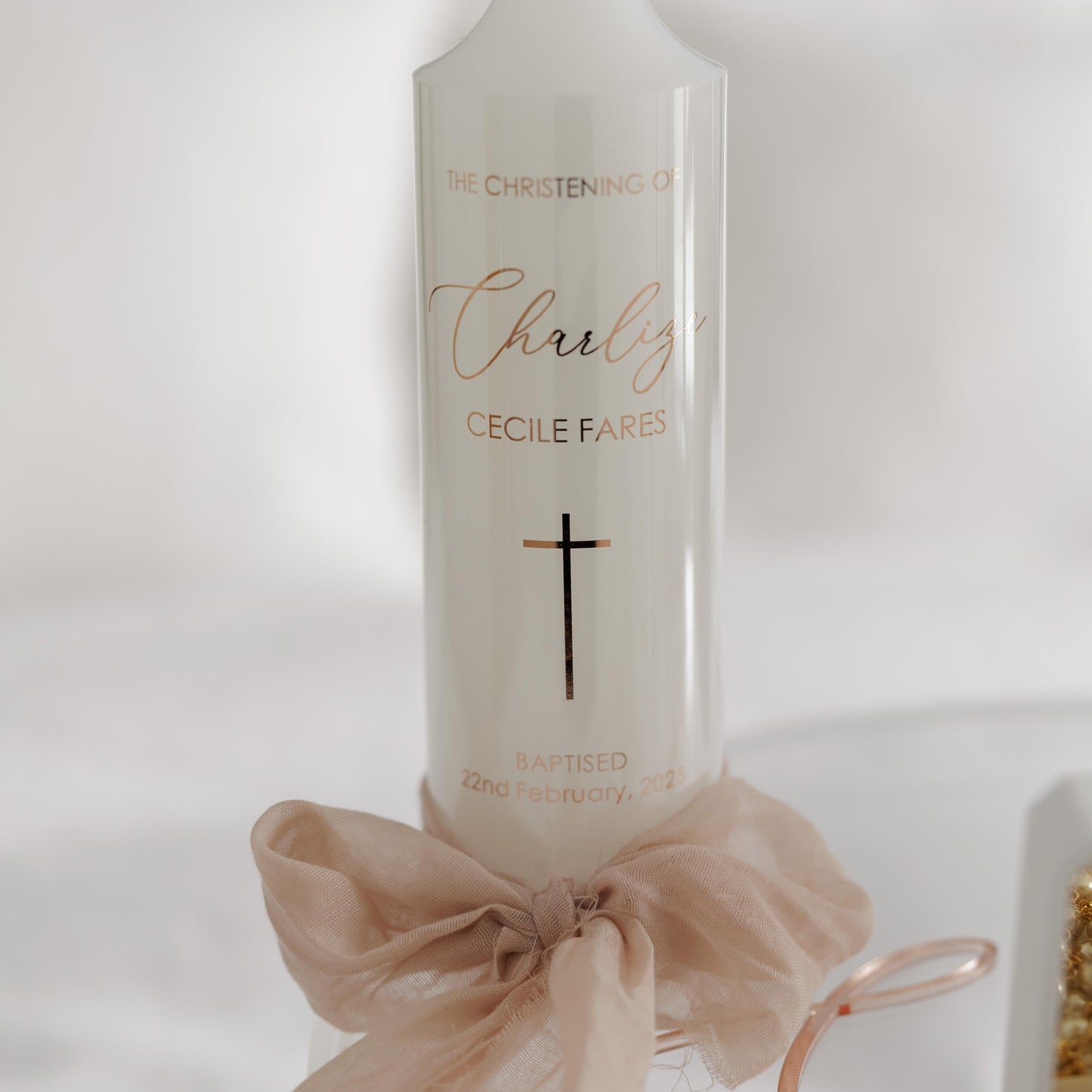 Elegant personalised Christening candle with a gold script name, cross design, and baptism date, adorned with a soft bow – perfect for a baptism keepsake.
