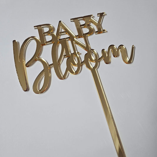 Gold mirror acrylic Baby in Bloom cake topper featuring elegant script and block lettering, perfect for floral-themed baby showers and gender reveal parties.