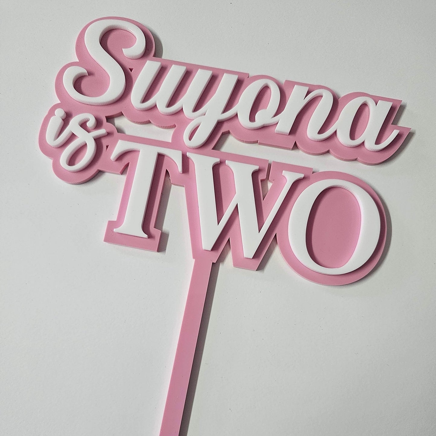 Custom "Suyona is Two" acrylic cake topper with stylish script, perfect for second birthday celebrations and milestone events.