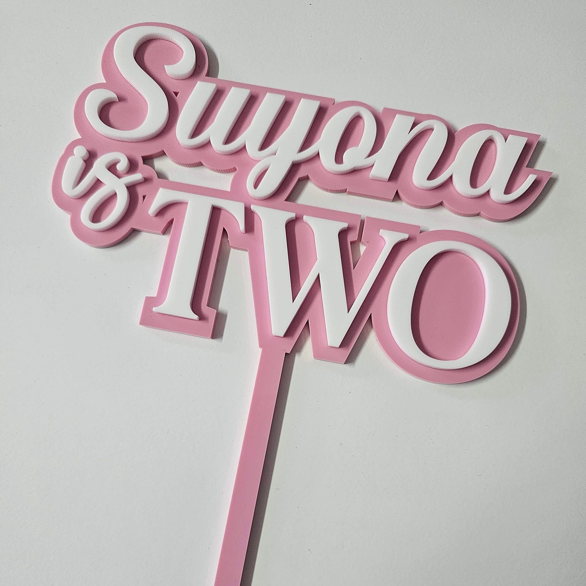 Custom "Suyona is Two" acrylic cake topper with stylish script, perfect for second birthday celebrations and milestone events.