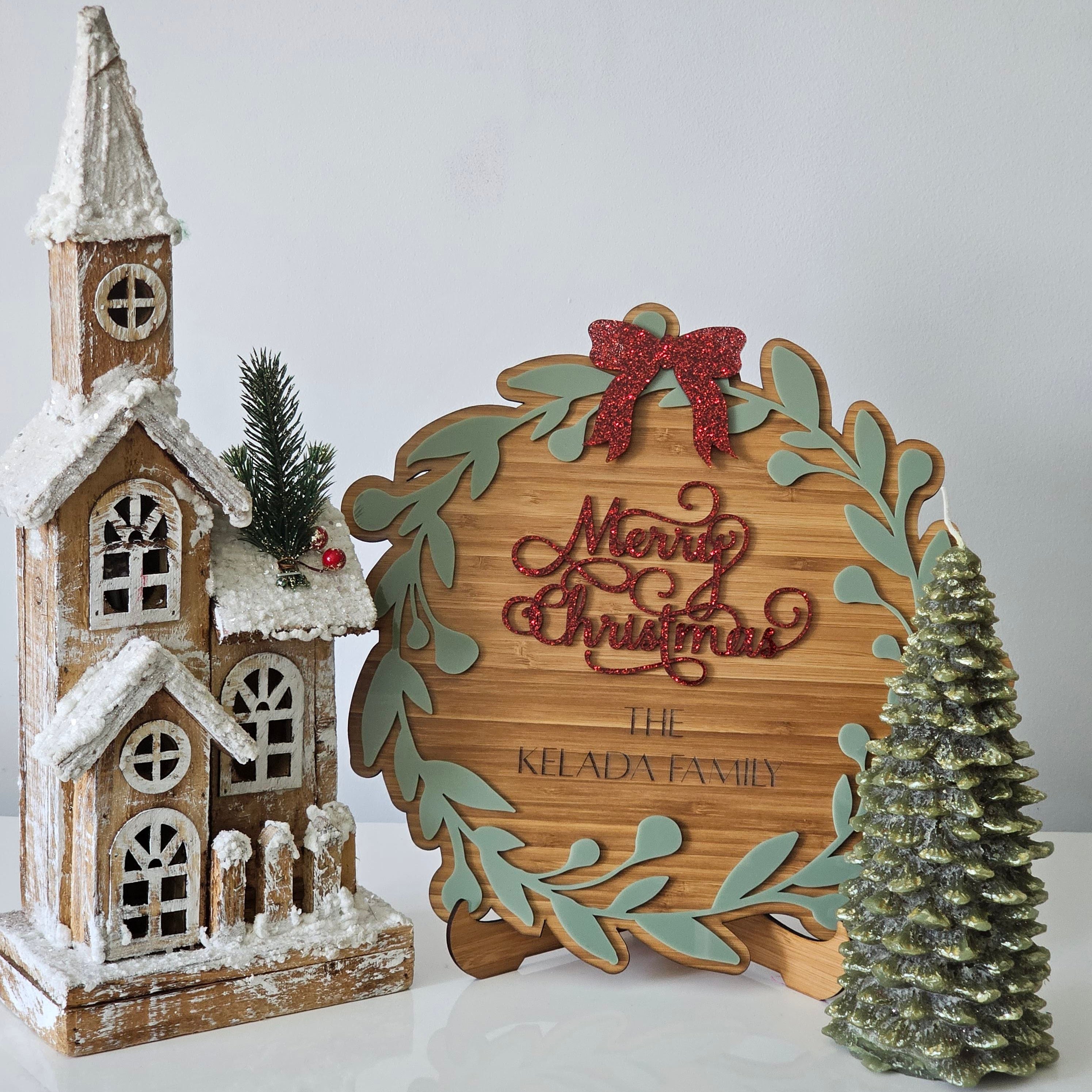 Christmas plaque with red “Merry Christmas” text, wreath design, and personalised family name, styled with festive decorations.