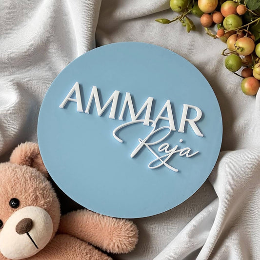Round personalised newborn name plaque with white script, blue background, teddy bear and berry accents – custom colours and fonts available.