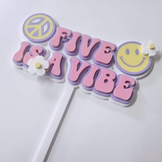 "Five Is a Vibe" double-layer acrylic cake topper with pink and purple bubble letters, a peace sign, smiley face, and white daisy accents, perfect for a 5th birthday.
