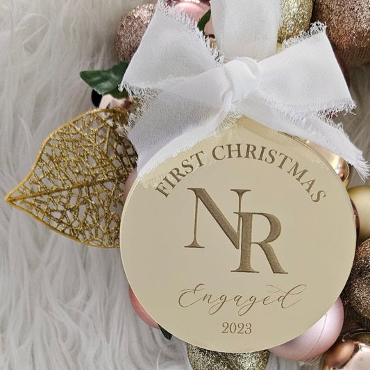 Personalised engagement-themed Christmas ornament with initials, “First Christmas Engaged 2023” text, ribbon bow, and festive baubles.